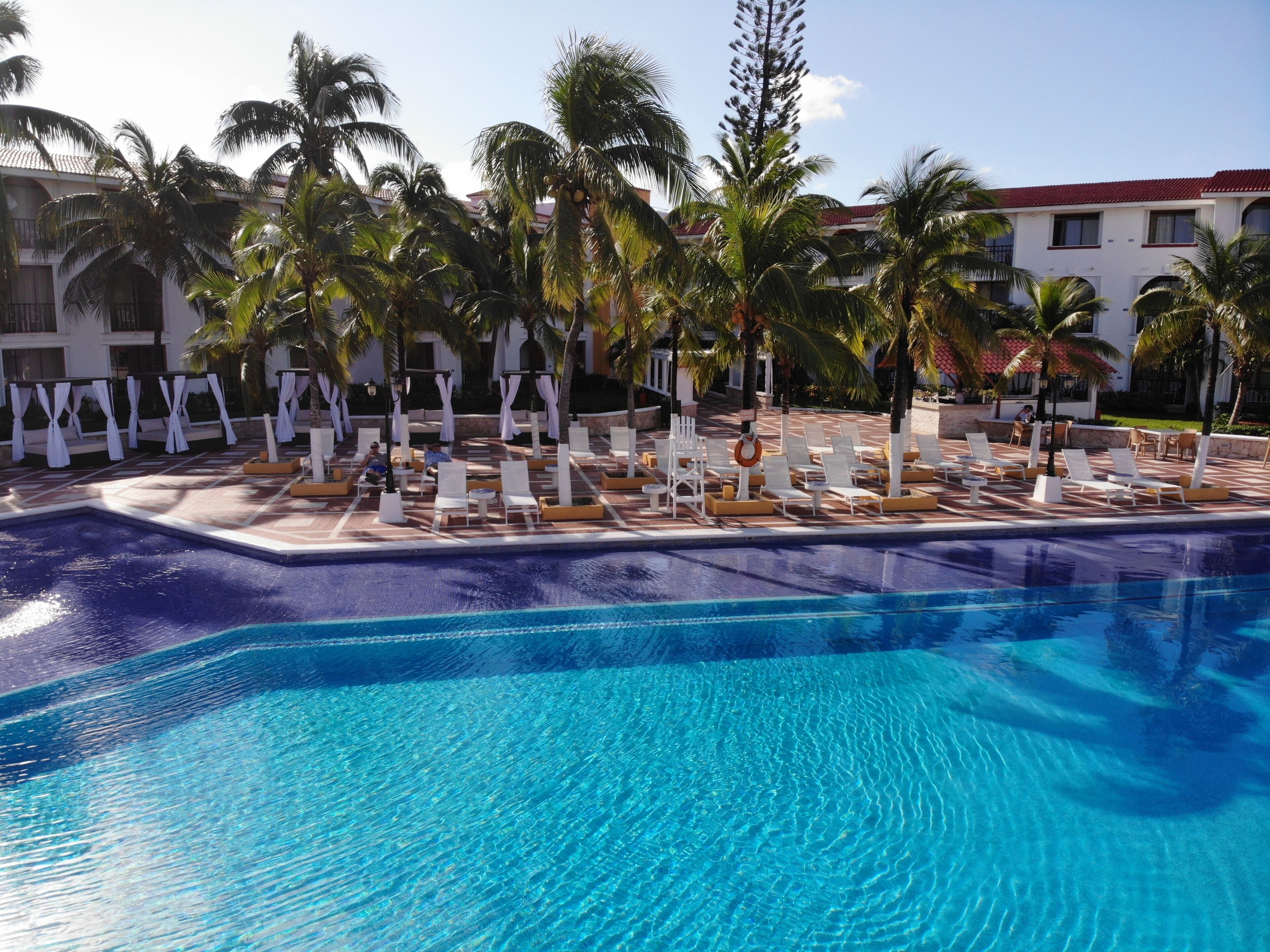 A pool area with lounge chairs and palm trees.