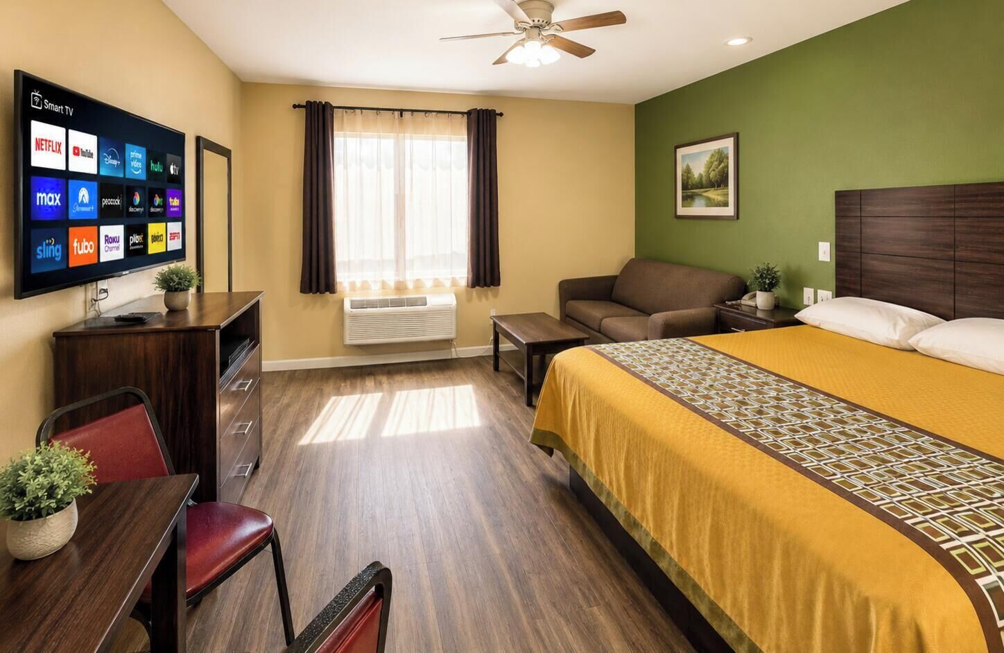 Hotelkamer met een bed, bureau, stoel, bank en een televisie waarop streamingdiensten worden vertoond, plus een raam met gordijnen.