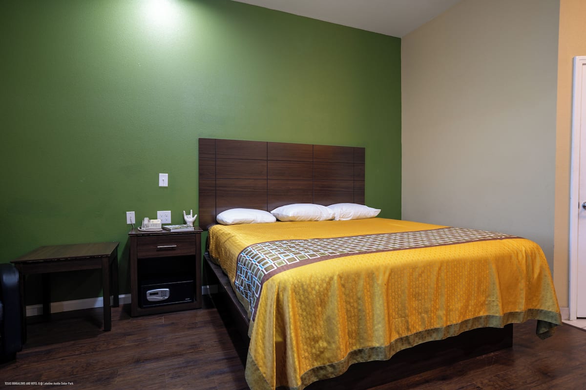 Un dormitorio con cama, mesita de noche, una pequeña mesa y una puerta.