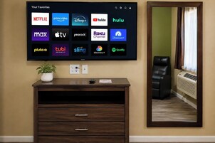 Televisão de tela plana fixada na parede exibindo diversos logotipos de serviços de streaming.