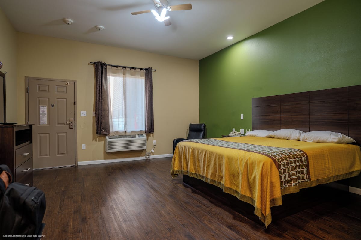 Un dormitorio con cama, una silla, un escritorio y una puerta.