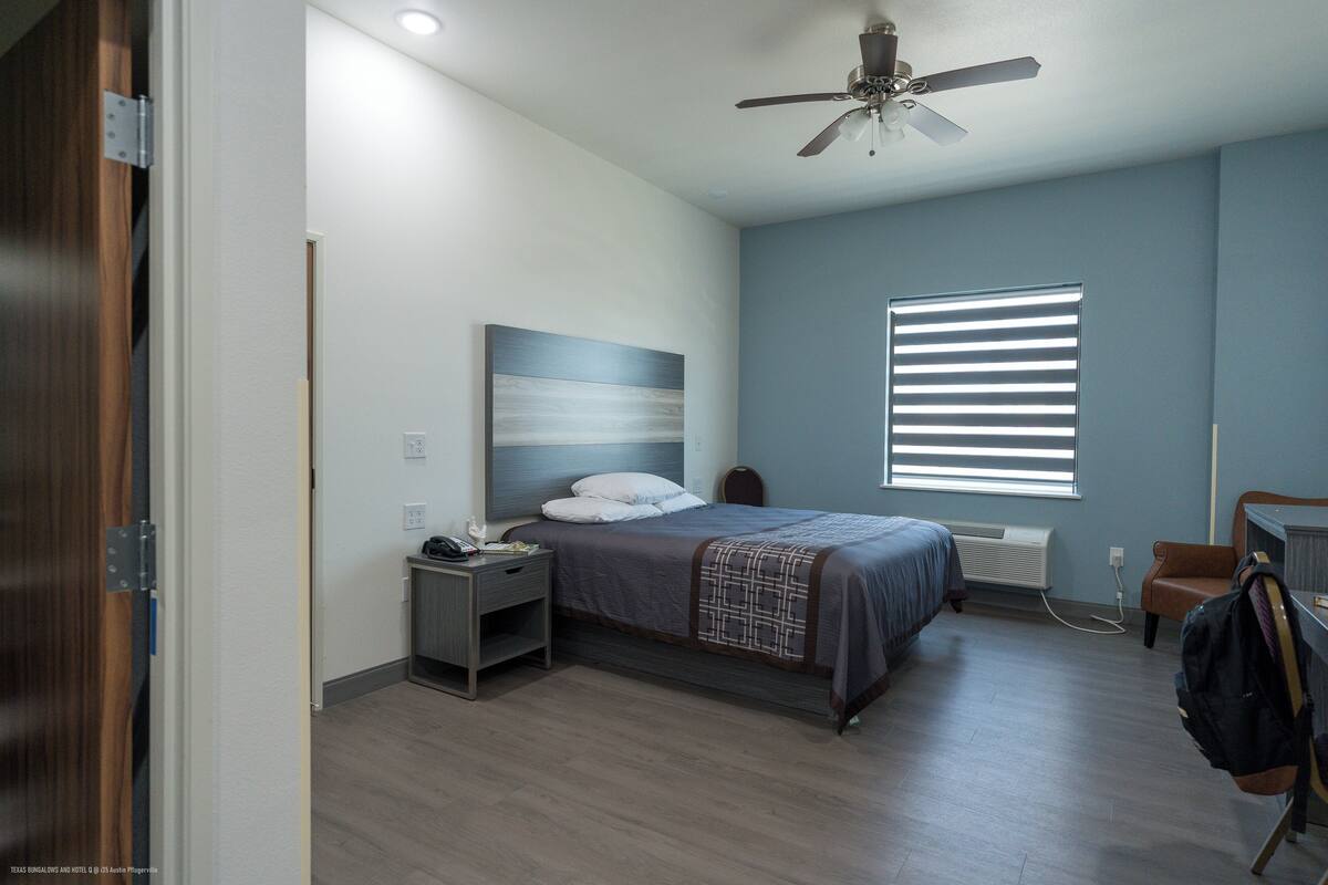 Un dormitorio con cama, mesita de noche y ventilador de techo.