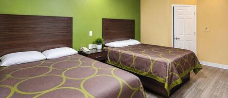 A hotel room with two beds, a wooden headboard, a green wall, a yellow wall, and a wooden floor.