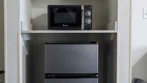 A compact kitchenette with a microwave and a refrigerator. - Texas Bungalows Hotel & Hotel Que at Lakeline Austin Cedar Park (Cedar Park)