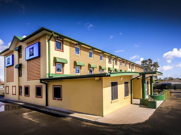 A two-story building with a flat roof, multiple windows, and a green awning.