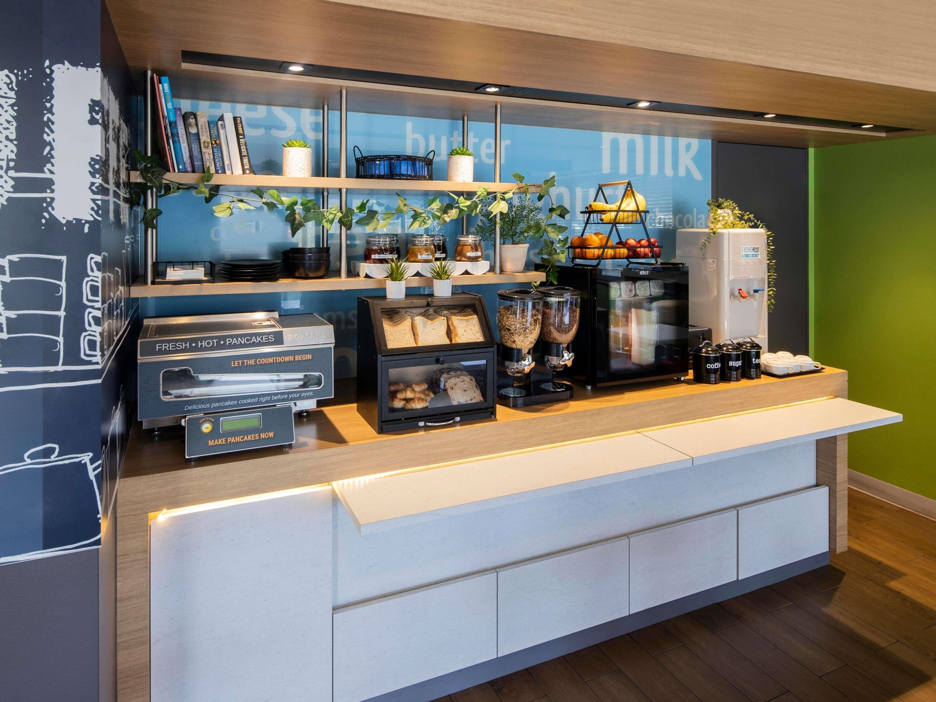 A breakfast bar with a coffee machine, a toaster, and a display of fresh bread and pastries.