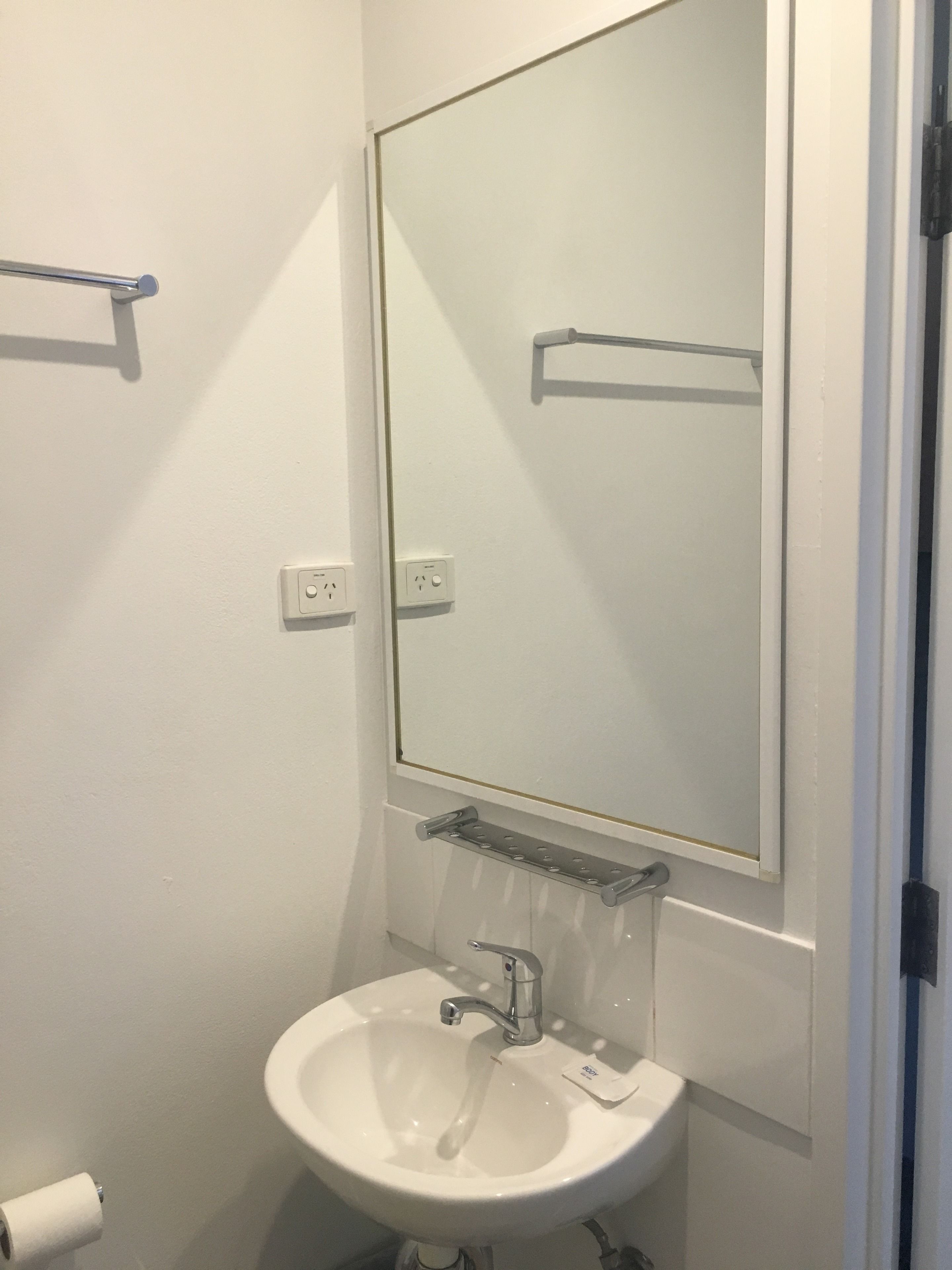 Une salle de bain avec un lavabo blanc, un miroir et deux porte-serviettes.