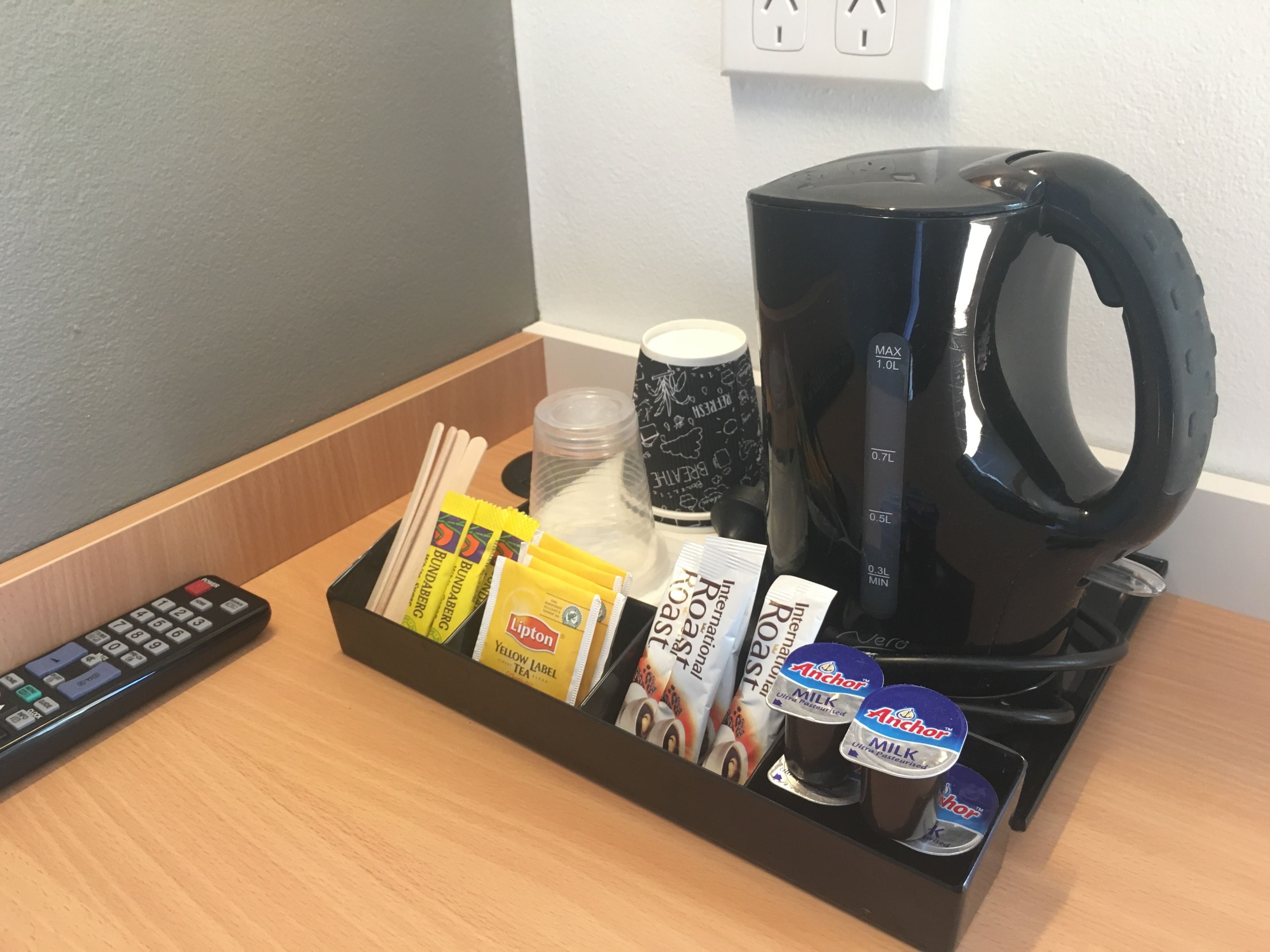 Un coin café équipé d’une machine à café, de sachets de thé et d’une télécommande.