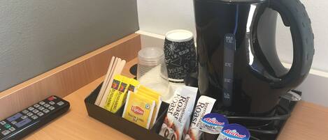 Un coin café équipé d’une machine à café, de sachets de thé et d’une télécommande.