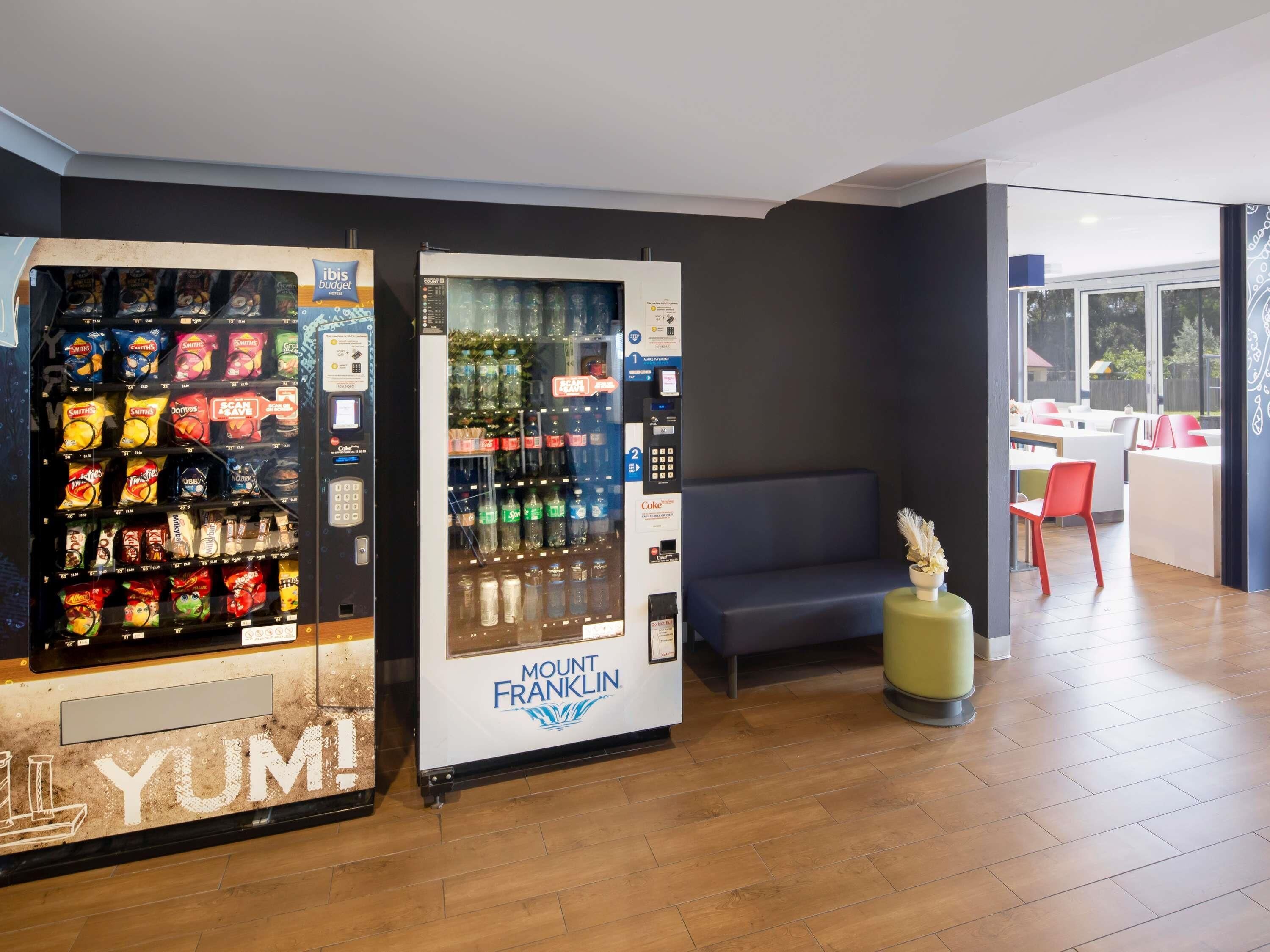 Zona de máquinas expendedoras con aperitivos y bebidas, un espacio de descanso y vistas al exterior.