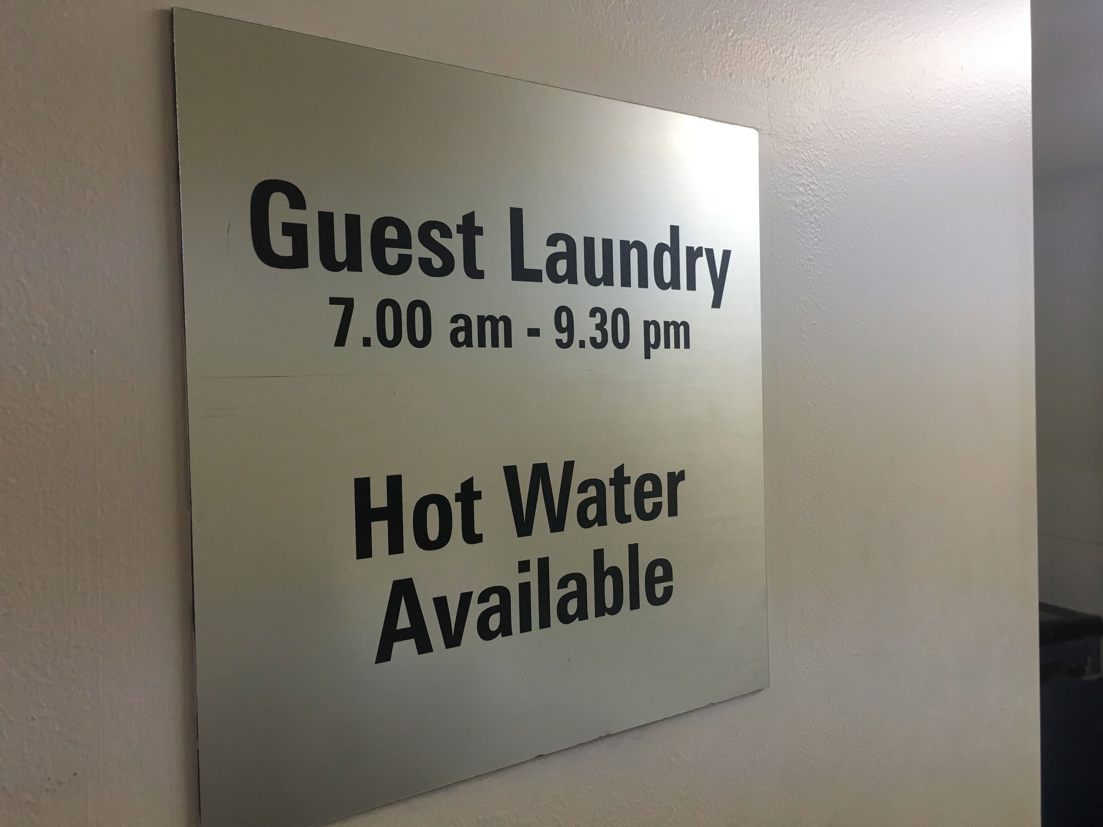 Schild mit Angabe der Öffnungszeiten der Gästewäsche von 7:00 bis 21:30 Uhr und Hinweis auf die Verfügbarkeit von Warmwasser.