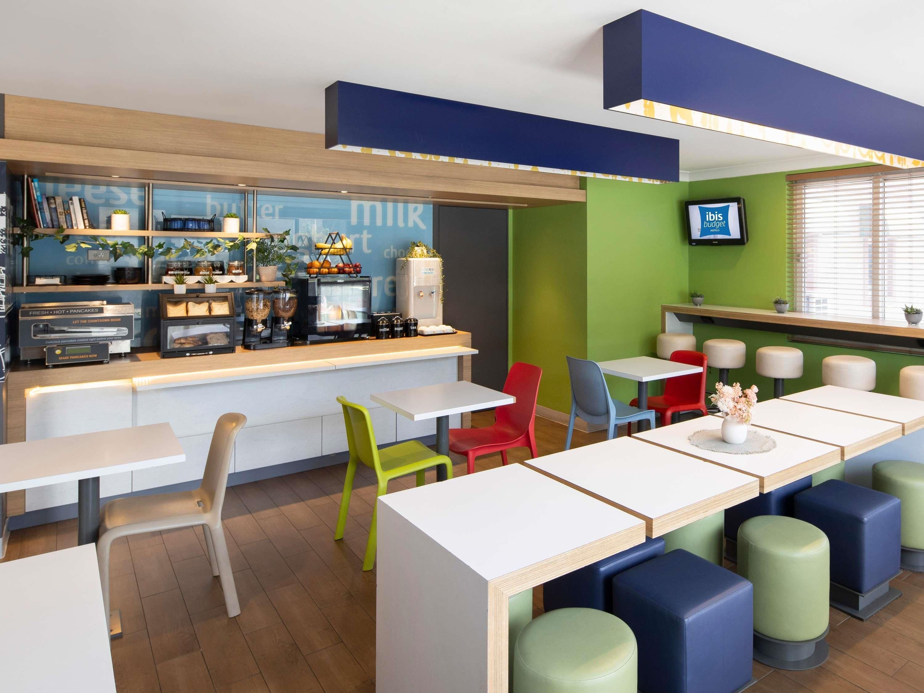 A modern cafe with a counter, seating area, and a TV screen.