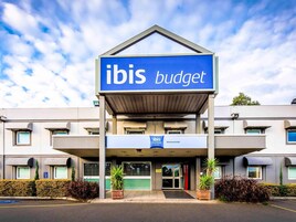 Un hotel llamado ibis budget con un diseño moderno, una entrada cubierta y un área de estacionamiento.