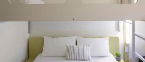 A bed with white bedding, a striped pillow, and a green nightstand.