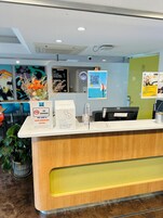 Una mesa de recepción de hotel con un letrero de prohibido fumar, un código QR para el registro digital y un cartel que indica que el hotel es para no fumadores.