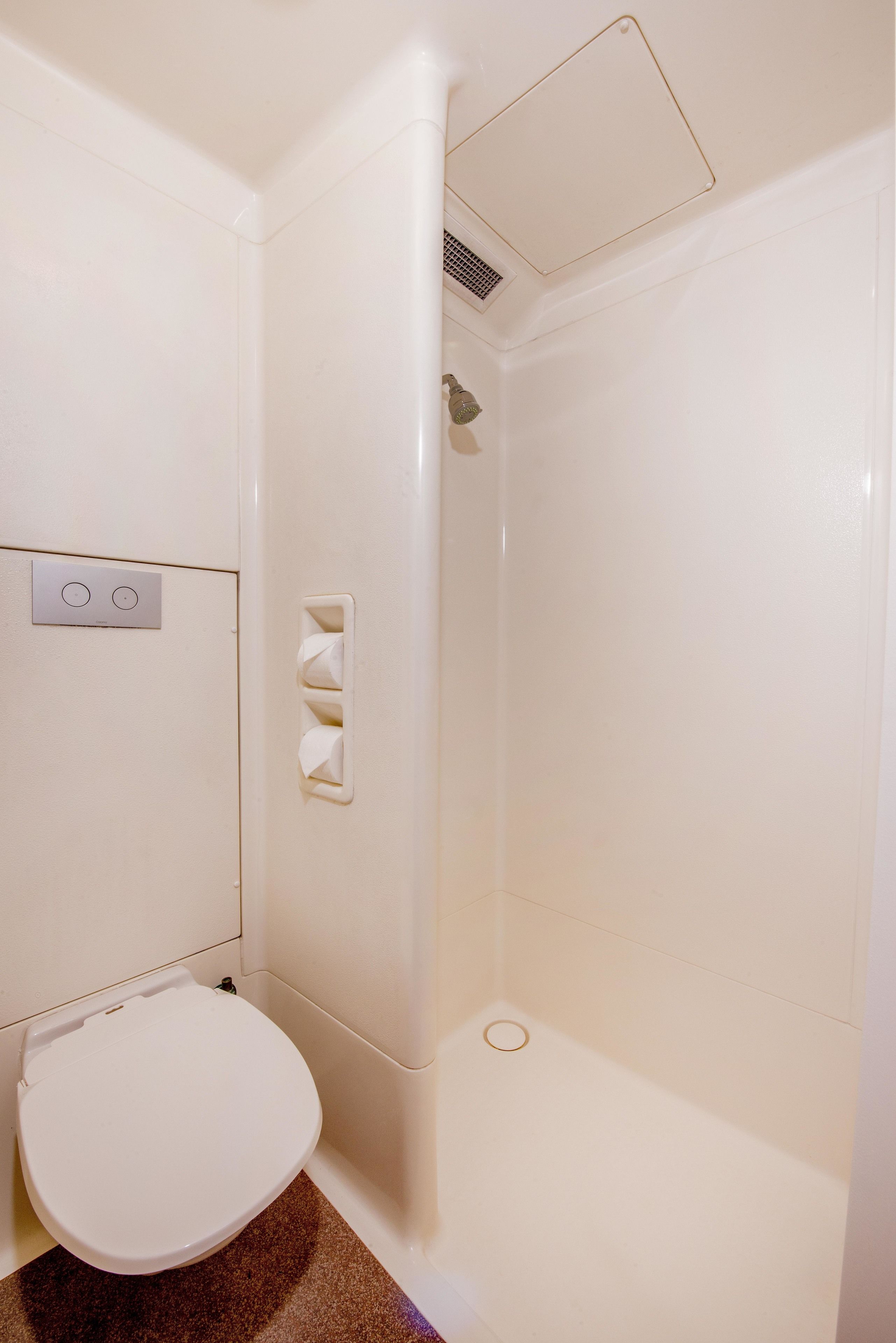 A bathroom with a toilet, a shower, and a hand dryer.