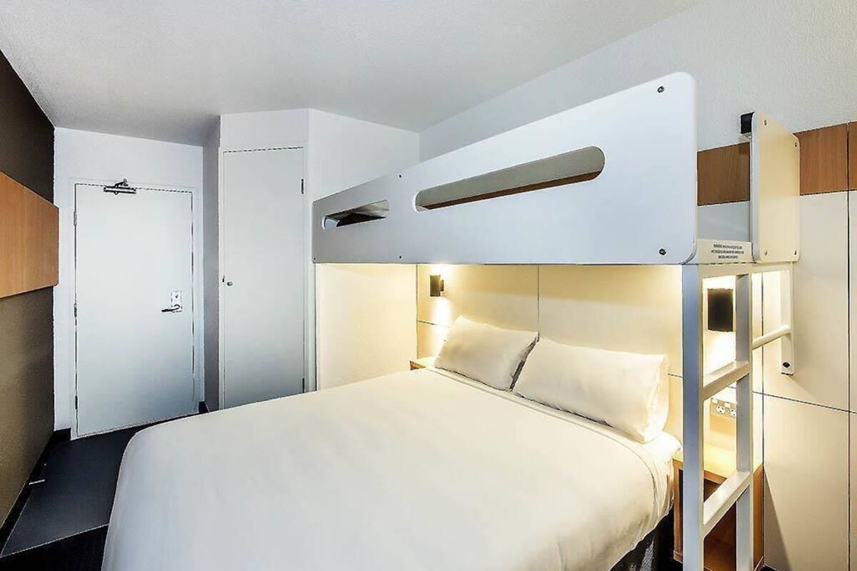 Un lit superposé avec une tête de lit, une table de chevet et une étagère fixée au mur.