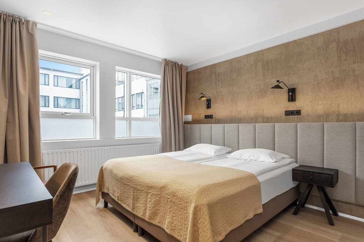 Hotellihuone, jossa on sänky, työpöytä ja tuoli.