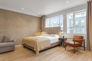 Una camera d'albergo con un letto, una sedia, una scrivania e una finestra vista edifici.