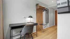 Una habitación moderna y compacta con escritorio, silla y una planta colgante.