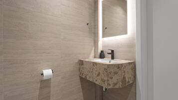 Un baño con inodoro, lavabo con encimera de mármol y espejo.