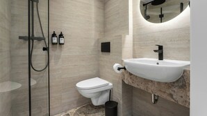 Un baño moderno con cabina de ducha de vidrio, inodoro y lavabo con encimera de mármol.