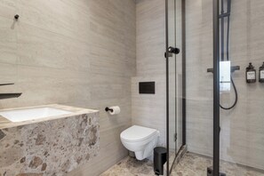 Un bagno moderno con lavabo in marmo, toilette e cabina doccia in vetro.