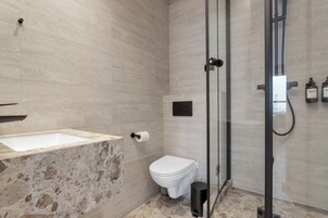 Un baño moderno con lavamanos, inodoro y ducha con cerramiento de vidrio de mármol.