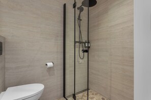 Un baño moderno con cabina de ducha de vidrio, inodoro y toallero.