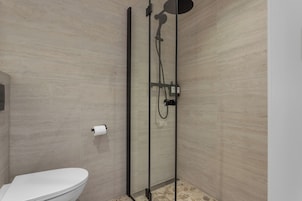 A modern bathroom with a glass-enclosed shower, a toilet, and a towel rack.