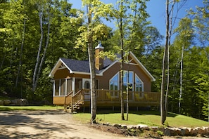 A cabin with a porch, large windows, and a chimney. - Chalets Lanaudiere (Rawdon)