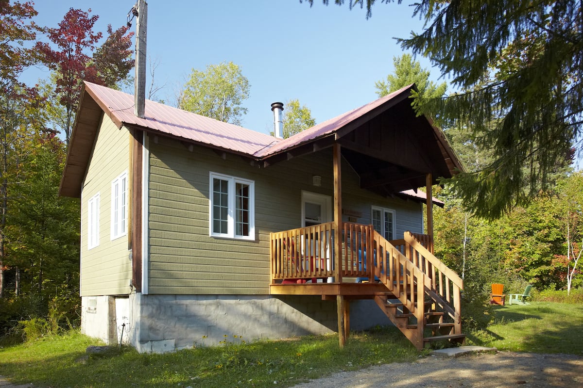 A two-story cabin with a wooden deck and a chimney.