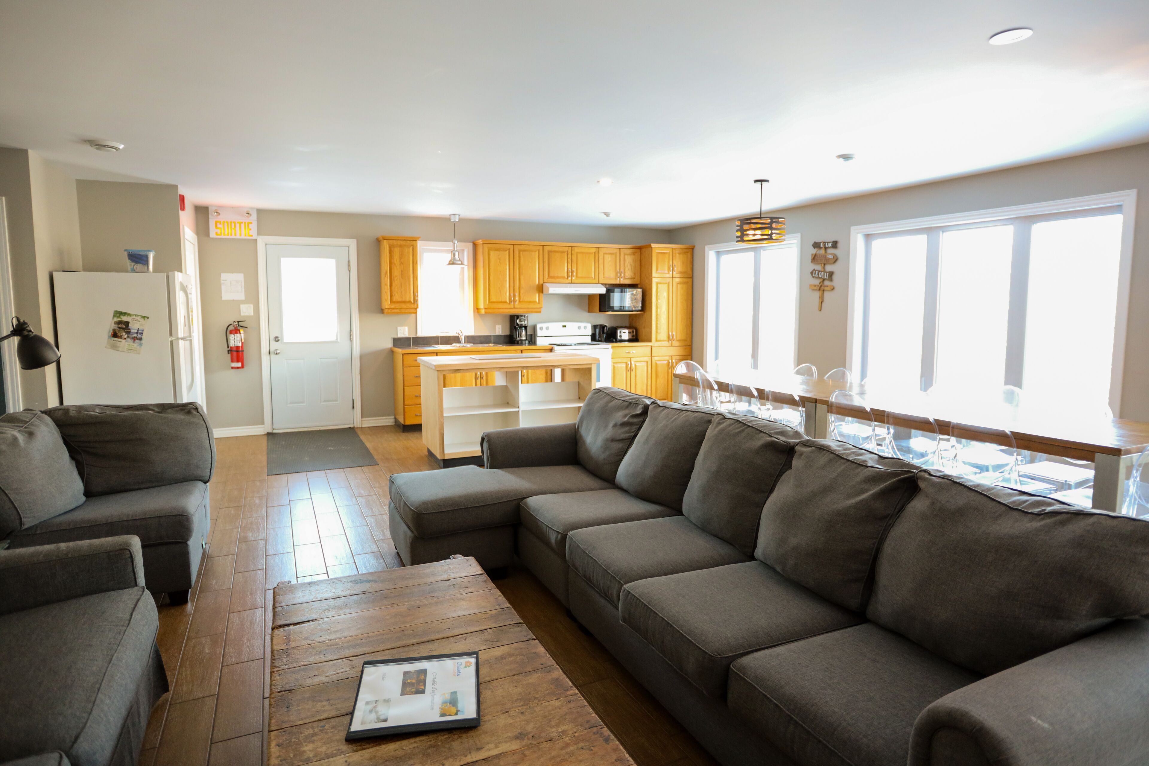 A modern living room with a sectional sofa, a coffee table, and a kitchen in the background.