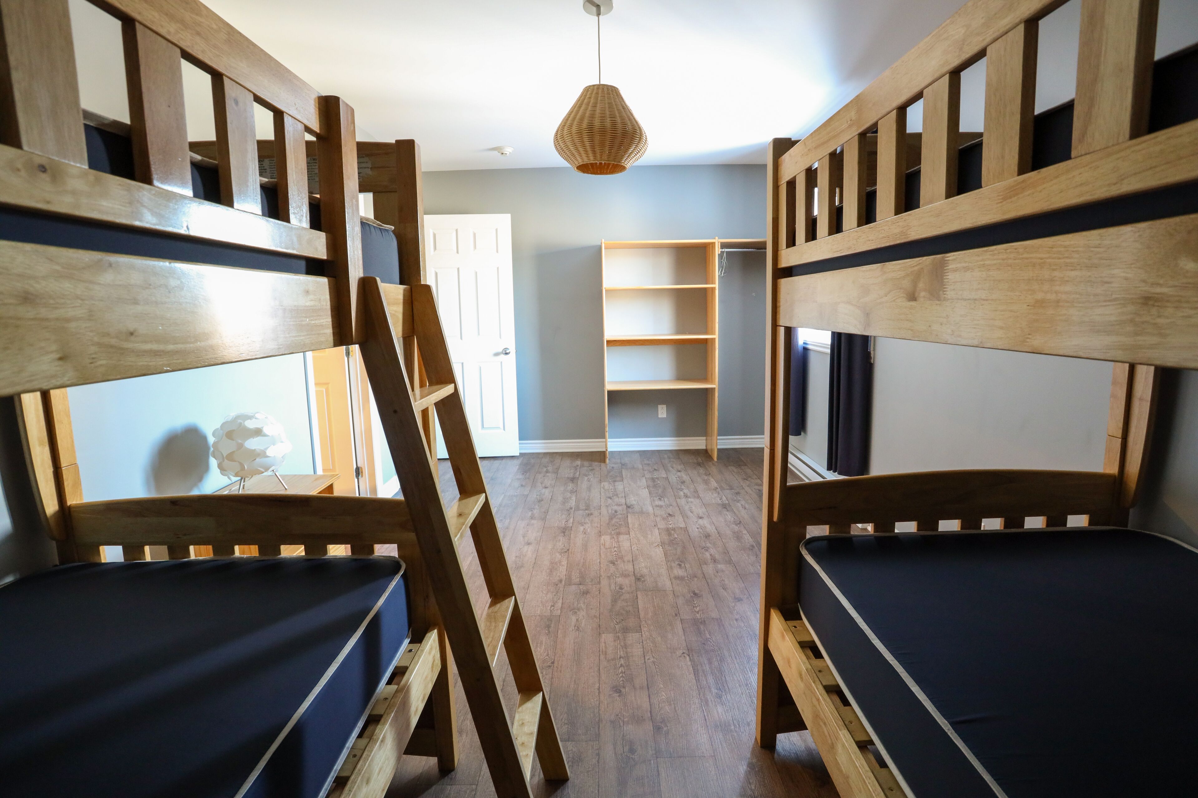 Una habitación con literas, una escalera y una lámpara colgante.
