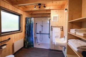 A wooden cabin bathroom with a shower, sink, and towel rack. - Chalets Lanaudiere (Rawdon)