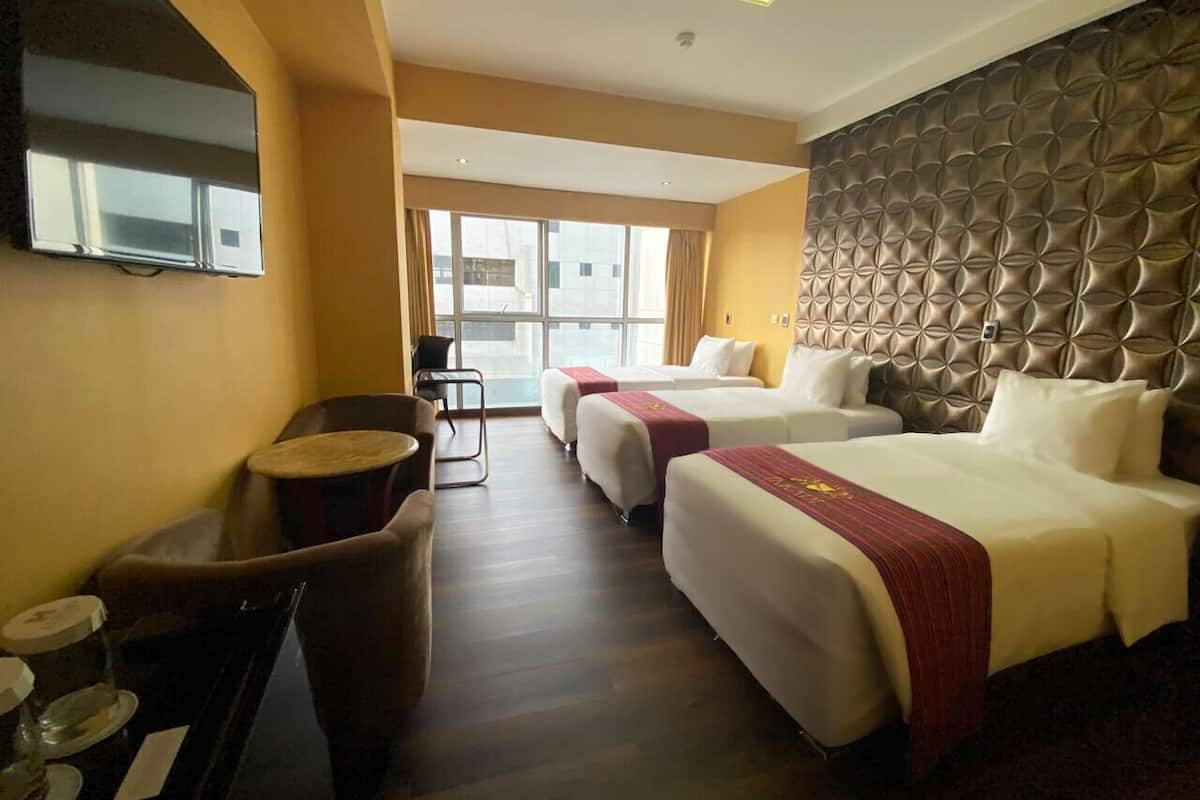 A hotel room with two beds, a sofa, a small table, and a TV.