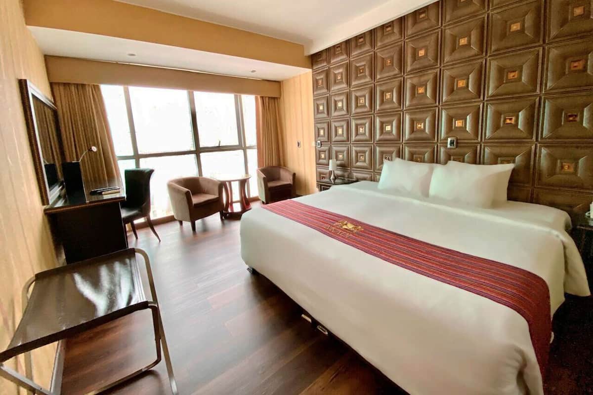 A hotel room with a large bed, a desk, a chair, and a TV.
