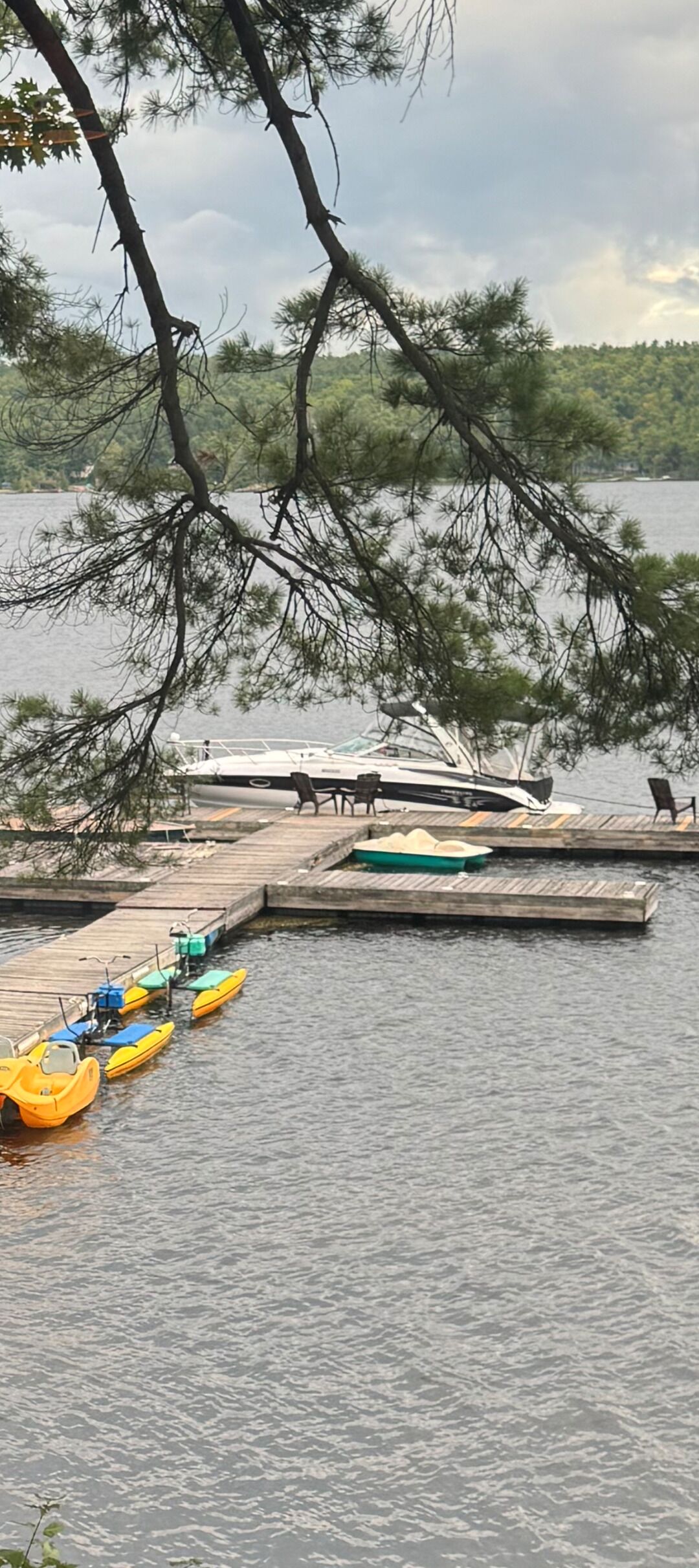 A dock with several boats and a small green boat in the water.