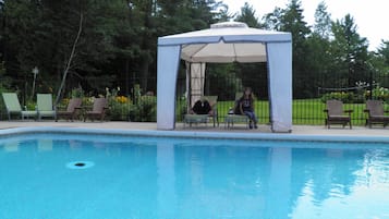 Una piscina al aire libre de temporada, sillones reclinables de piscina