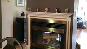 A fireplace with a mantel decorated with figurines, a framed picture above it, and a hanging light fixture on the wall. - The Boston 'T' B&B (Ottawa)