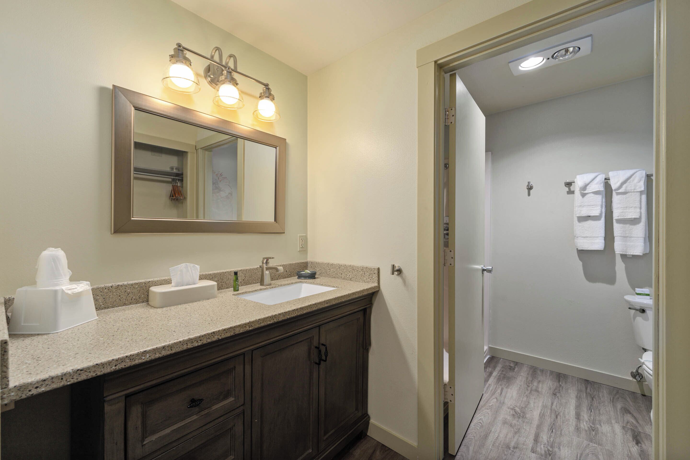 A bathroom with a double sink vanity, a large mirror, and a shower area.