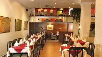 A restaurant with long tables, chairs, and a high ceiling with recessed lighting.