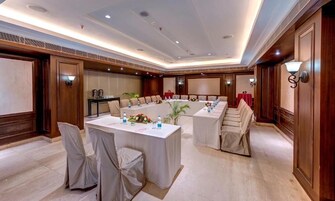 Un salón de conferencias con una larga mesa, sillas y una pequeña tarima.