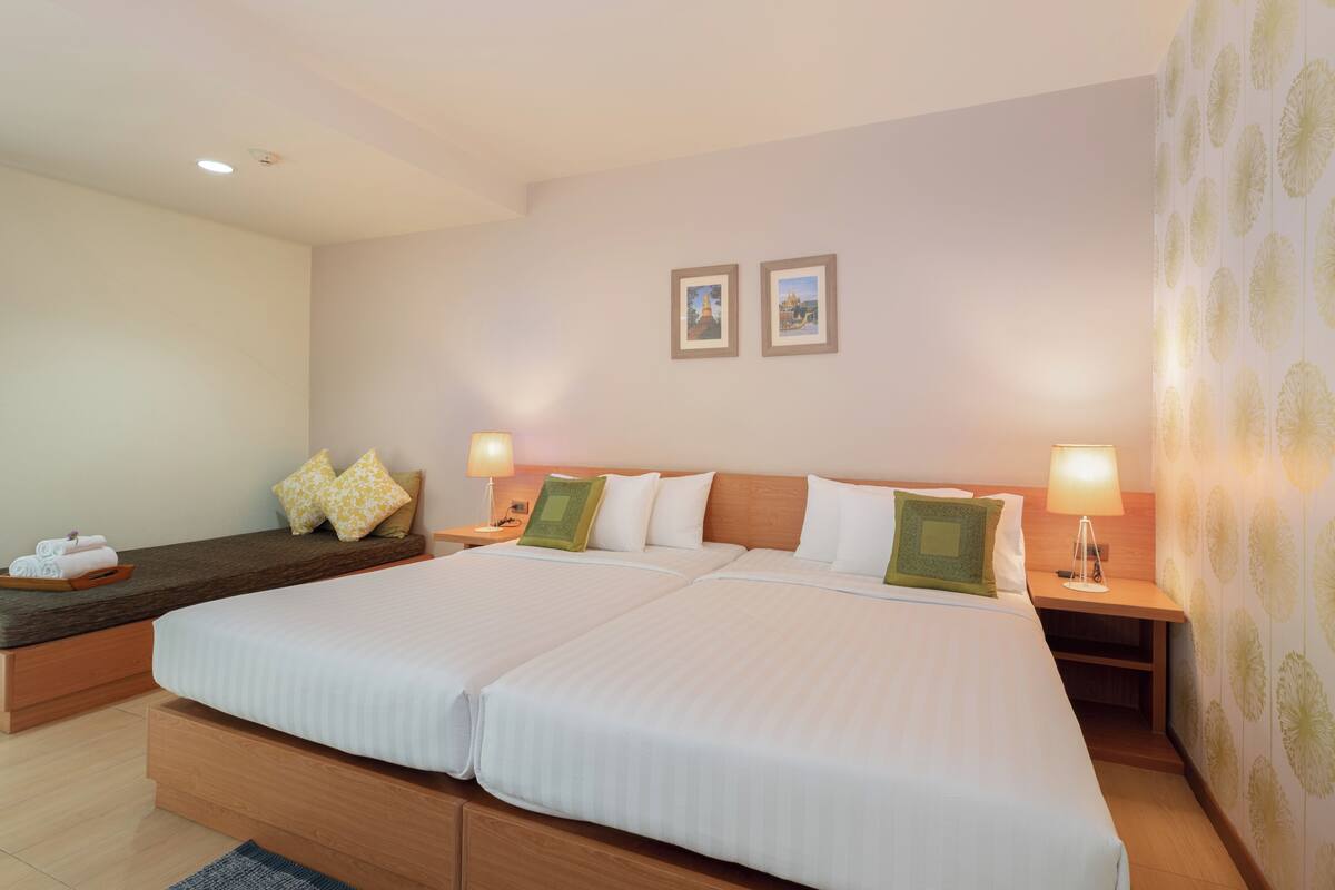 A double bed with two nightstands, a bench, and two wall-mounted picture frames.