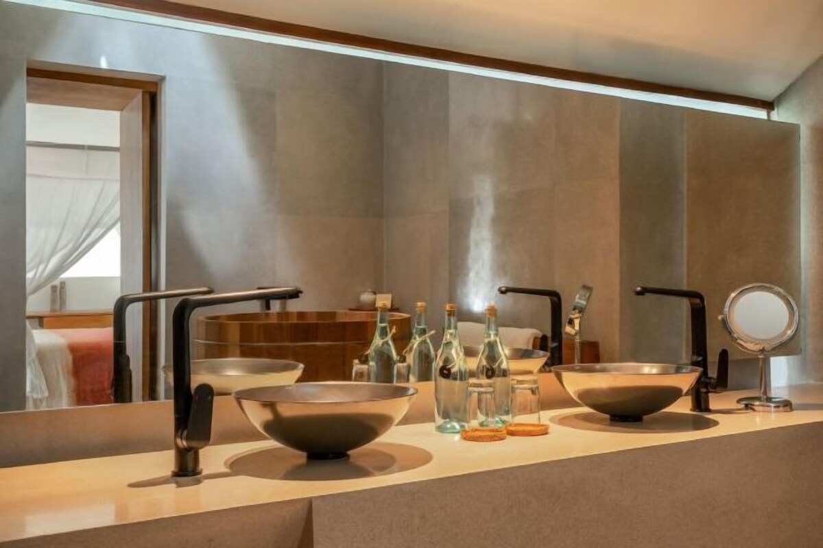 A modern bathroom with two sinks, a large mirror, and a towel rack.