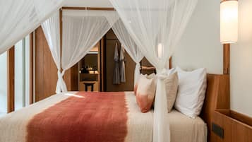 A bed with a red and beige blanket, white pillows, and a canopy.