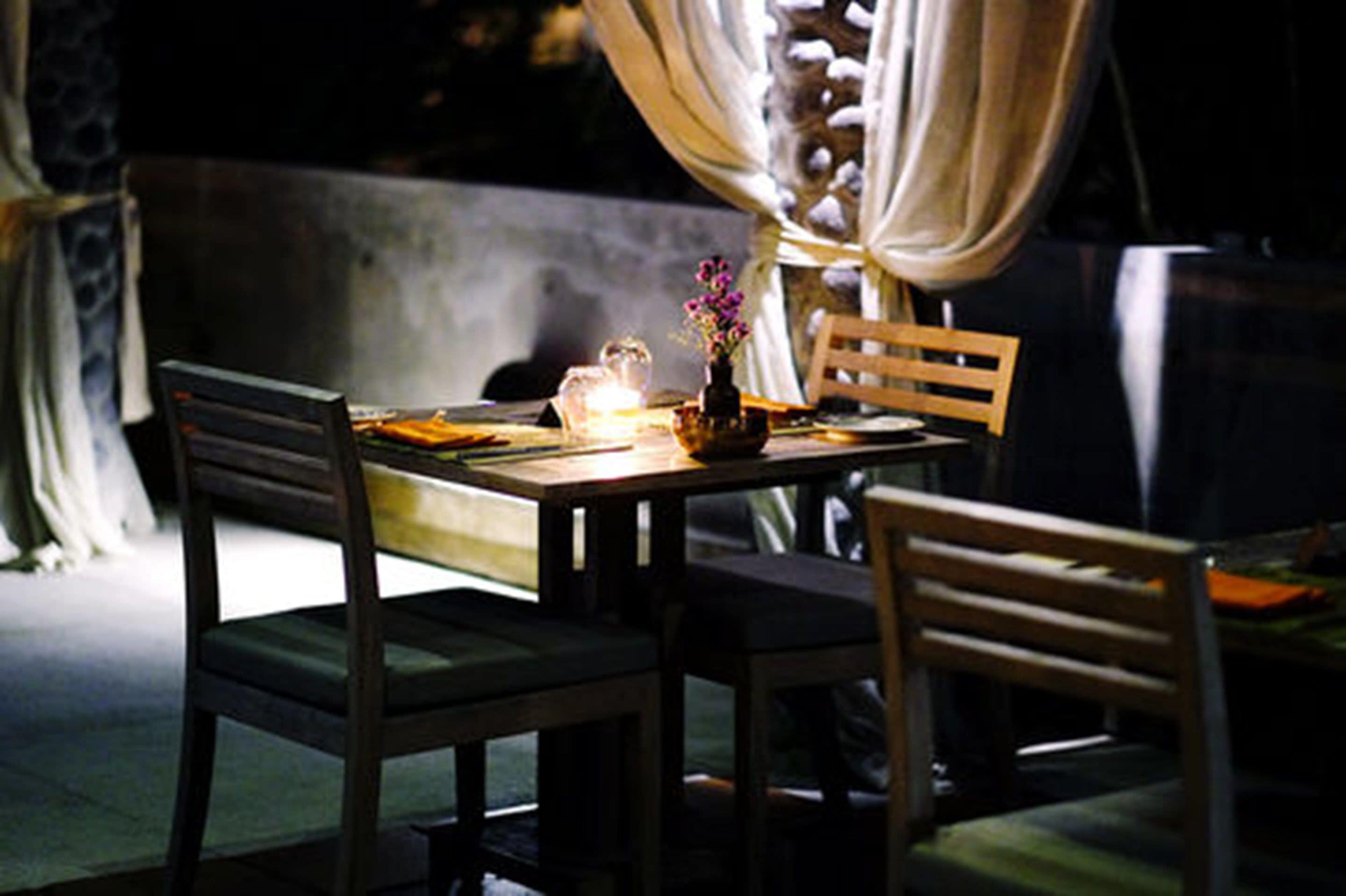 A dining table with chairs, a vase with flowers, and a candle.