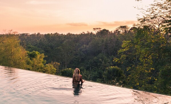 Una piscina al aire libre, sombrillas, sillones reclinables de piscina