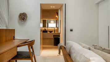 Une chambre moderne avec un bureau en bois, un lit avec une literie blanche et un miroir au-dessus du lit.