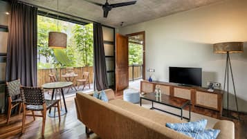 A modern living room with a sofa, chairs, a coffee table, a TV, and a balcony with plants.